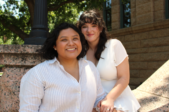 Two models smiling in front of building