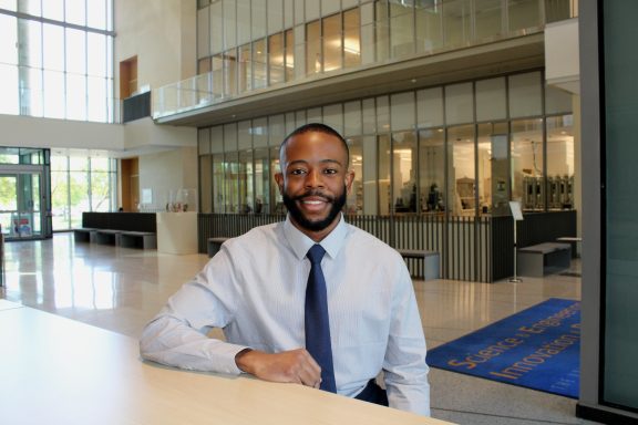 Model in professional clothing seated smiling in glass lab building