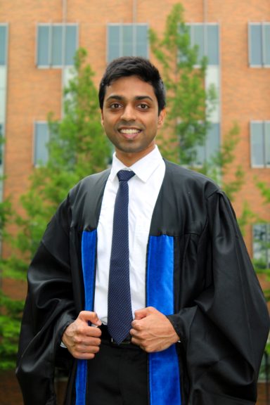 model in graduate regalia smiling